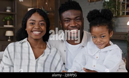 Parents africains heureux de famille avec fille écofille enfant fille s'asseoir à la maison allumer la télévision avec télécommande regarder en ligne programme musique spectacle amusant Banque D'Images