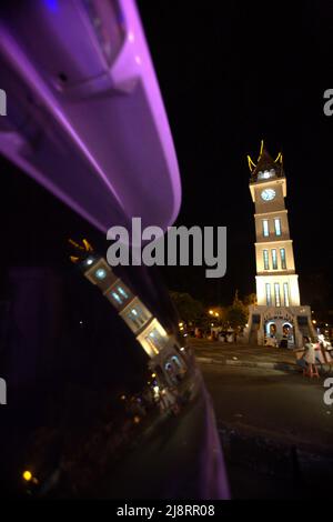 Grande tour d'horloge connue localement sous le nom de Jam Gadang et son reflet sur le verre de voiture, à Bukittinggi, Sumatra Ouest, Indonésie. Banque D'Images