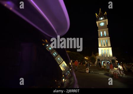 Grande tour d'horloge connue localement sous le nom de Jam Gadang et son reflet sur le verre de voiture, à Bukittinggi, Sumatra Ouest, Indonésie. Banque D'Images