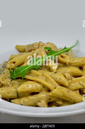 Poulet Alfredo pâtes avec épinards isolés sur blanc. Mise au point sélective. Banque D'Images