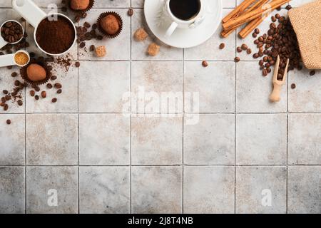 Fond de café. Cuillères à mesurer avec du café moulu, des haricots, une tasse et des truffes au chocolat doux sur un fond de table vieux carrelage fissuré. La nourriture. Banque D'Images