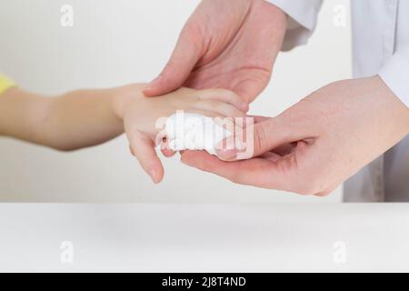 Les mains du médecin bandent le doigt douloureux avec un bandage de l'enfant.Blessure et blessure au doigt chez les enfants Banque D'Images