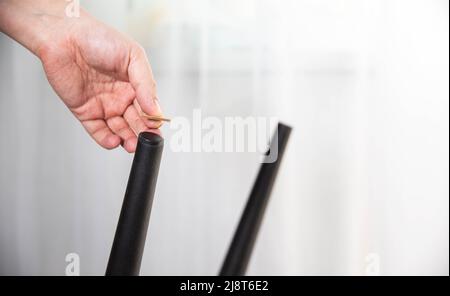 Un homme colle des coussins protecteurs sur les pieds d'une chaise. Protection contre les rayures et le bruit du sol, intérieur Banque D'Images