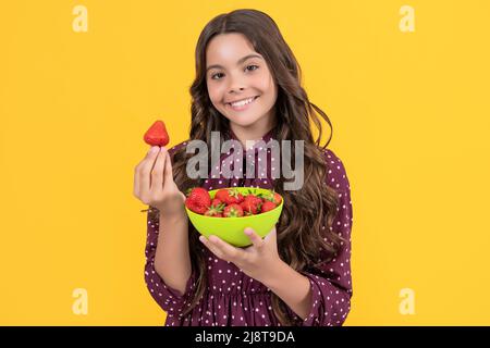 joyeux enfant de l'adolescence tenir le bol de fraise sur fond jaune Banque D'Images