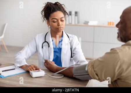 Femme noire médecin vérifiant la pression de mesure sur la main du patient Banque D'Images