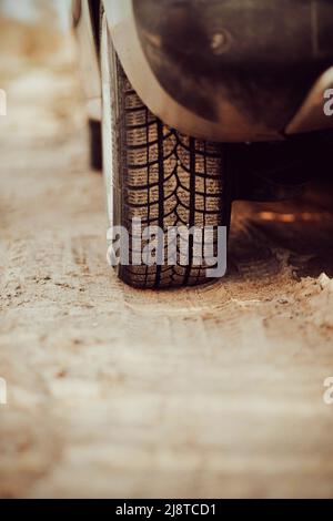 Vue arrière d'une voiture rétro poussiéreuse debout avec des roues sur le sable. Impression de pneus sur le sable par temps ensoleillé. Banque D'Images