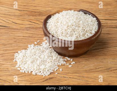 Riz carnaroli risotto cru dans un bol sur table en bois. Banque D'Images