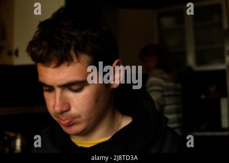 Recentrer le portrait du jeune homme dans la cuisine sombre. Portrait sombre millénaire. Santé mentale. Hors foyer. Banque D'Images