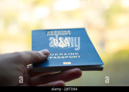 Recentrer le passeport d'un citoyen ukrainien dans une main féminine sur un fond urbain flou, gros plan. Inscription au passeport ukrainien. Guerre. Par Banque D'Images