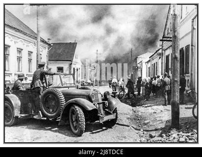 WW2 1940s Front de l'est opération Barbarrossa Un incendie dans une ville sur le front de l'est. Une voiture de tourisme Mercedes d'officier de Wehrmacht avec des soldats allemands nazis au premier plan avec des résidents locaux observant l'action. Deuxième Guerre mondiale Banque D'Images