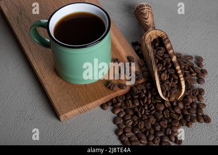 Tasse de café verte avec grains de café sur fond de béton Banque D'Images