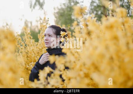 Portrait d'une jeune femme posant dans un jardin de printemps en fleurs. Fille entourée de fleurs Banque D'Images