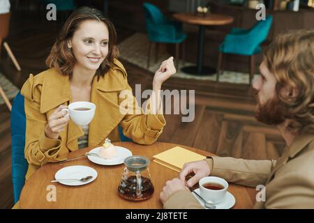 Portrait d'un homme moderne sérieux avec barbe assis à table ronde dans le café loft et appelant par téléphone portable Banque D'Images