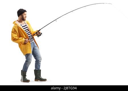 Photo pleine longueur d'un jeune homme dans un imperméable et des bottes de pêche avec une tige isolée sur fond blanc Banque D'Images