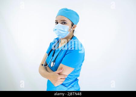 Belle femme médecin portant uniforme et bleu capuchon chirurgical, masque facial et gants en latex. Femme professionnelle sur fond blanc Banque D'Images