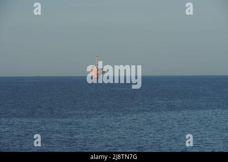 Vue à l'horizon sur une plate-forme de couleur orange pour l'extraction de pétrole et de gaz naturel dans la mer Adriatique près de la côte italienne. Banque D'Images