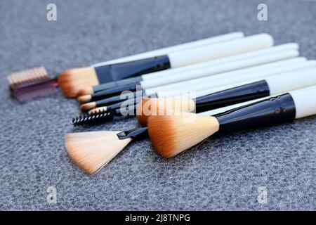 gros plan sur le faisceau blanc brun kit de maquillage brossez sur fond gris brun non focus. Banque D'Images