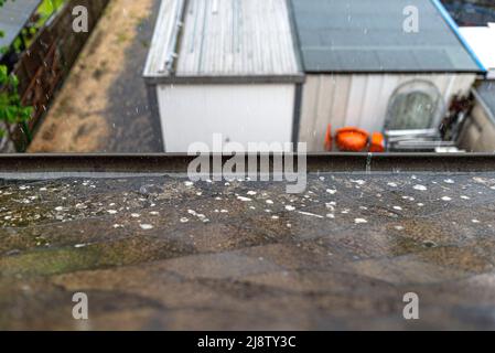 Forte pluie tombant sur le toit débordant la gouttière avec de l'eau par temps pluvieux. Banque D'Images