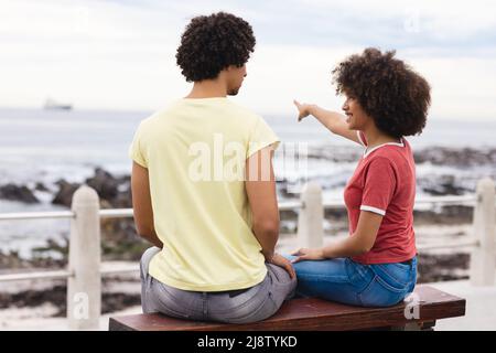 Jeune femme afro souriante pointant vers la mer pour le petit ami afro-américain Banque D'Images