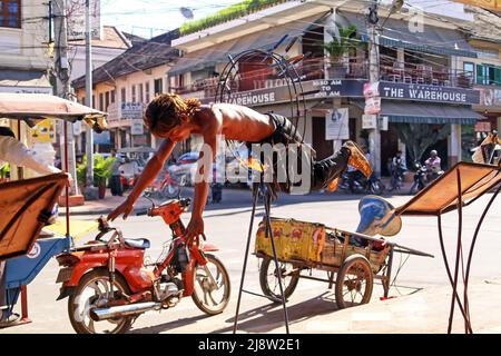 Siem Reap, Cambodge - décembre 9. 2011: Jeune artiste de rue khmer cambodgien sautant à travers le feu anneau de cerceau avec des couteaux pointus en face du restaurant Banque D'Images