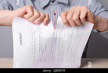 Homme mains déchirant le document. Rupture de contrat. Résiliation de la coopération, refus de renouveler l'accord. Violation des sanctions, conditions et obligations. Photo de haute qualité Banque D'Images