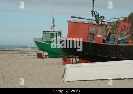 De vieux bateaux se tiennent sur la plage au bord de la mer. Un vieux bateau de pêche à éplucher se trouve sur la rive. Un filet de pêche est suspendu sur un bateau. La texture du vieux bois. Banque D'Images