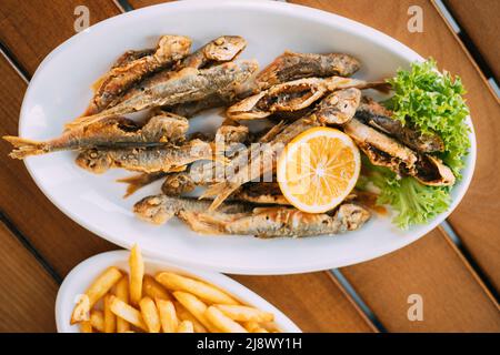 Plat de cuisine nationale géorgienne : poisson-mulet avec frites et orange. Poisson et frites Banque D'Images