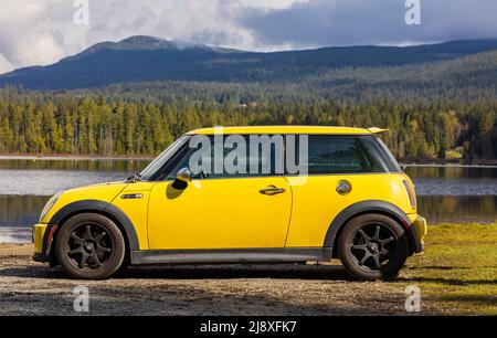 Vue latérale d'une voiture jaune Mini Cooper S sur fond naturel. Mini Cooper jaune garée dans le parc-27 avril,2022-Lac Whonnock C.-B., Canada-pho Voyage Banque D'Images