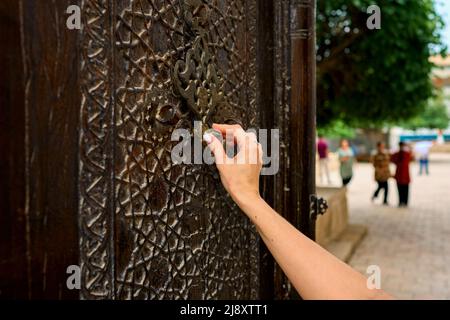 la main d'une femme frappe sur une vieille porte Banque D'Images