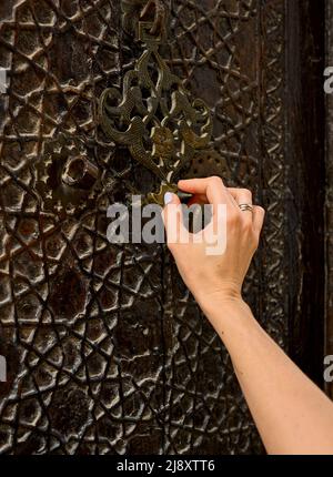 la main d'une femme frappe sur une vieille porte Banque D'Images