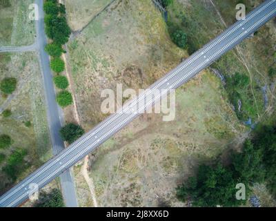 Voies ferrées vue aérienne montrant des lignes de chemin de fer parallèles, des arbres verts, des terres agricoles et des routes asphaltées dans la campagne australienne. Banque D'Images