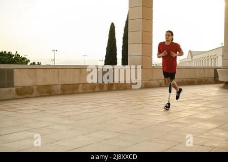 Athlète masculin avec un handicap courir à l'extérieur. Homme avec une jambe prothétique en train de courir. Banque D'Images