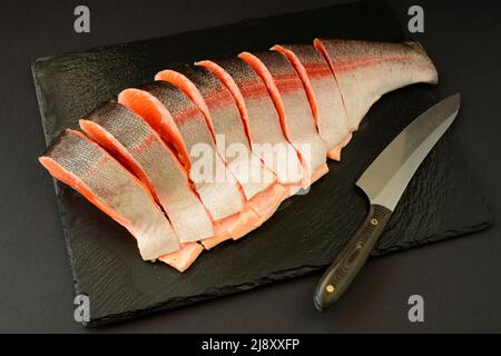 Couper et préparer du poisson rouge frais cru, de la truite, du saumon pour cuire ou rôtir sur un grill, barbecue Banque D'Images