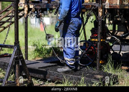 Un travailleur de l'industrie pétrolière et gazière exploite des tuyaux de forage de forage pétrolier sur un engin de forage de puits de pétrole. Banque D'Images