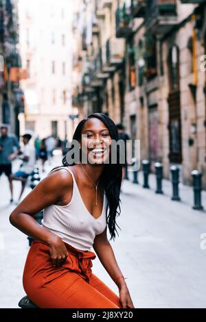 Jeune femme afro-américaine regardant la caméra et souriant à l'extérieur dans la rue de la ville. Banque D'Images