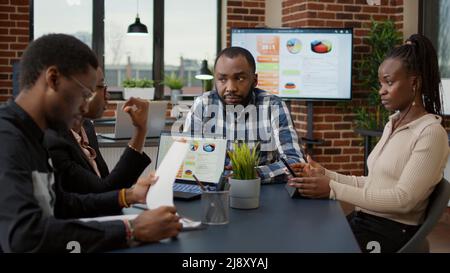 Les employés de l'entreprise travaillent en équipe sur des projets financiers, en utilisant une tablette numérique et un ordinateur portable pour analyser des graphiques statistiques et des graphiques de données. Groupe de personnes collaborant sur présentation. Réfléchissez à des idées. Banque D'Images