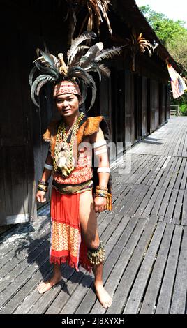 Un jeune homme de l'IBAN dans le chasseur de tête de guerrier régalia, y compris le headaddress de plumes de charme, au village culturel de Sarawak près de Kuching, Sarawak, Malaisie. Banque D'Images