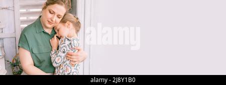 mère de famille heureuse avec petite fille fille fille dans la campagne de la banlieue vie à la maison le jour ensoleillé. mère candid tient l'enfant dans les bras et les câlins et se sent la douleur Banque D'Images