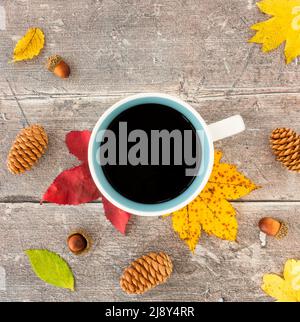 Vue de dessus des feuilles d'automne colorées, des feuilles d'automne, des glands, des pommes de pin et une tasse avec café noir sur bois rustique, abîmé, brun avec espace de copie. Banque D'Images