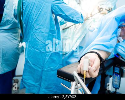 Gros plan d'un oxymètre de pouls sur le doigt d'un patient pendant la chirurgie. Mise au point sélective. Le patient se trouve dans la salle d'opération, sur la table d'opération. Banque D'Images