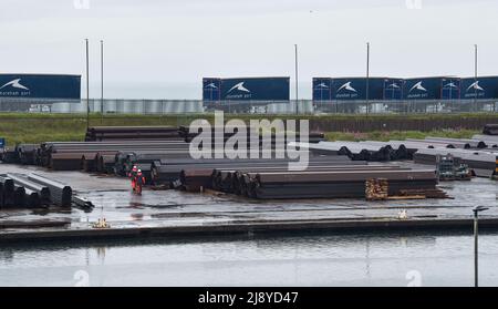 Brighton UK 19th mai 2022 - travailleurs portuaires sous la pluie sur un site de stockage de l'acier à Shoreham Port , Sussex après une nuit de tonnerre et de foudre le long de la côte sud : Credit Simon Dack / Alamy Live News Banque D'Images