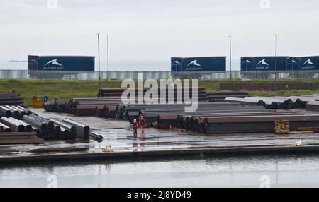 Brighton UK 19th mai 2022 - travailleurs portuaires sous la pluie sur un site de stockage de l'acier à Shoreham Port , Sussex après une nuit de tonnerre et de foudre le long de la côte sud : Credit Simon Dack / Alamy Live News Banque D'Images