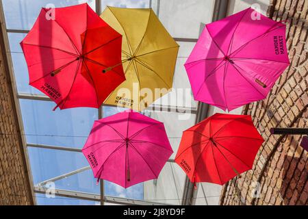 Parasols colorés avec les mots Camden Market font une caractéristique intéressante au-dessus d'une rangée de magasins au marché. Banque D'Images