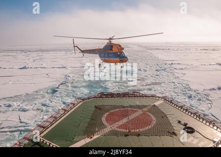 Un hélicoptère prend le décollage des 50 ans de victoire (50 Let Pobey) brise-glace nucléaire pendant que le navire navigue à travers la glace de mer Banque D'Images