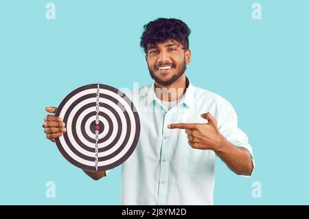 Portrait de l'homme hindou intelligent et positif avec un tableau de fléchettes qui symbolise la réalisation des buts. Banque D'Images