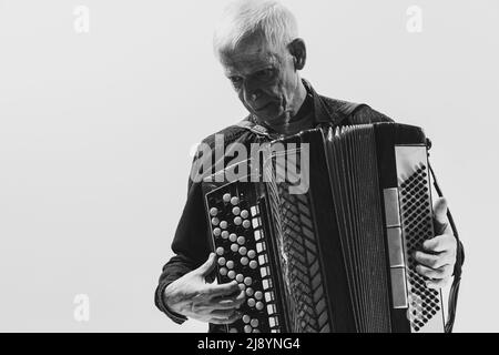 Portrait monochrome de l'homme séniot, musicien rétro jouant de l'accordéon isolé sur fond blanc. Concept d'art, de musique, de style, de génération ancienne Banque D'Images