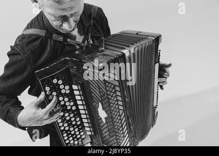 Portrait monochrome de l'homme séniot, musicien rétro jouant de l'accordéon isolé sur fond blanc. Concept d'art, de musique, de style, de génération ancienne Banque D'Images