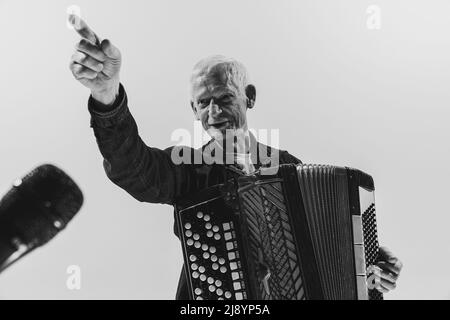 Portrait monochrome de l'homme séniot, musicien rétro jouant de l'accordéon isolé sur fond blanc. Concept d'art, de musique, de style, de génération ancienne Banque D'Images