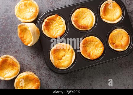 Des cheesecakes portugais traditionnels appelés queijadas de Sintra sont en gros plan dans un plat de cuisson sur la table. Vue horizontale du dessus Banque D'Images