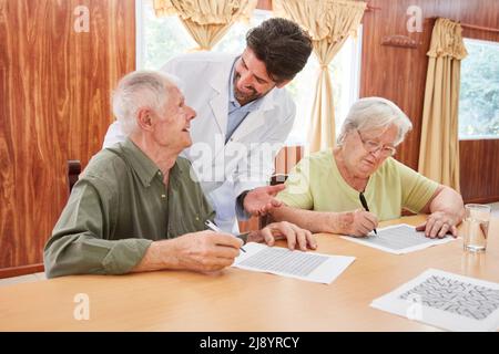 Un médecin ou une infirmière gériatrique prend soin d'un couple âgé atteint de démence pendant la formation à la mémoire en maison de soins infirmiers Banque D'Images